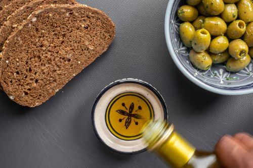 Olive oil in a bowl surrounded by bread and grapes